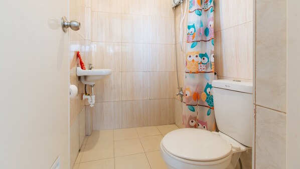 A small bathroom with a toilet, a sink, and a shower curtain with owl designs. - Reddoorz Near Christ the King Medical Center (Las Pinas)