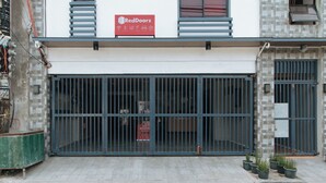 Une devanture de magasin fermée, avec une enseigne RedDoorz, des grilles métalliques et des plantes en pot sur le trottoir.