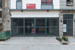 Een gesloten winkel met een RedDoorz bord, metalen hekken en plantenbakken op het trottoir.