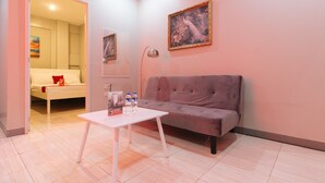 Een moderne woonkamer met een grijze bank, een witte salontafel en een schilderij aan de muur.
