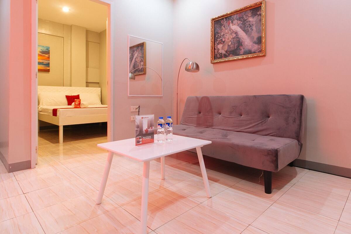 Een moderne woonkamer met een grijze bank, een witte salontafel en een schilderij aan de muur.