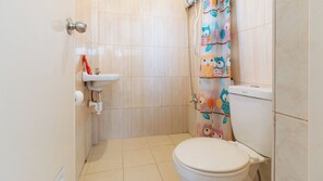 A small bathroom with a toilet, a sink, and a shower curtain with owl designs.