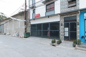 Un bâtiment portant l’enseigne RedDoorz, doté d’une entrée sécurisée par un portail et d’une porte bleue.