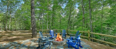 A fire pit with chairs in a forested area.