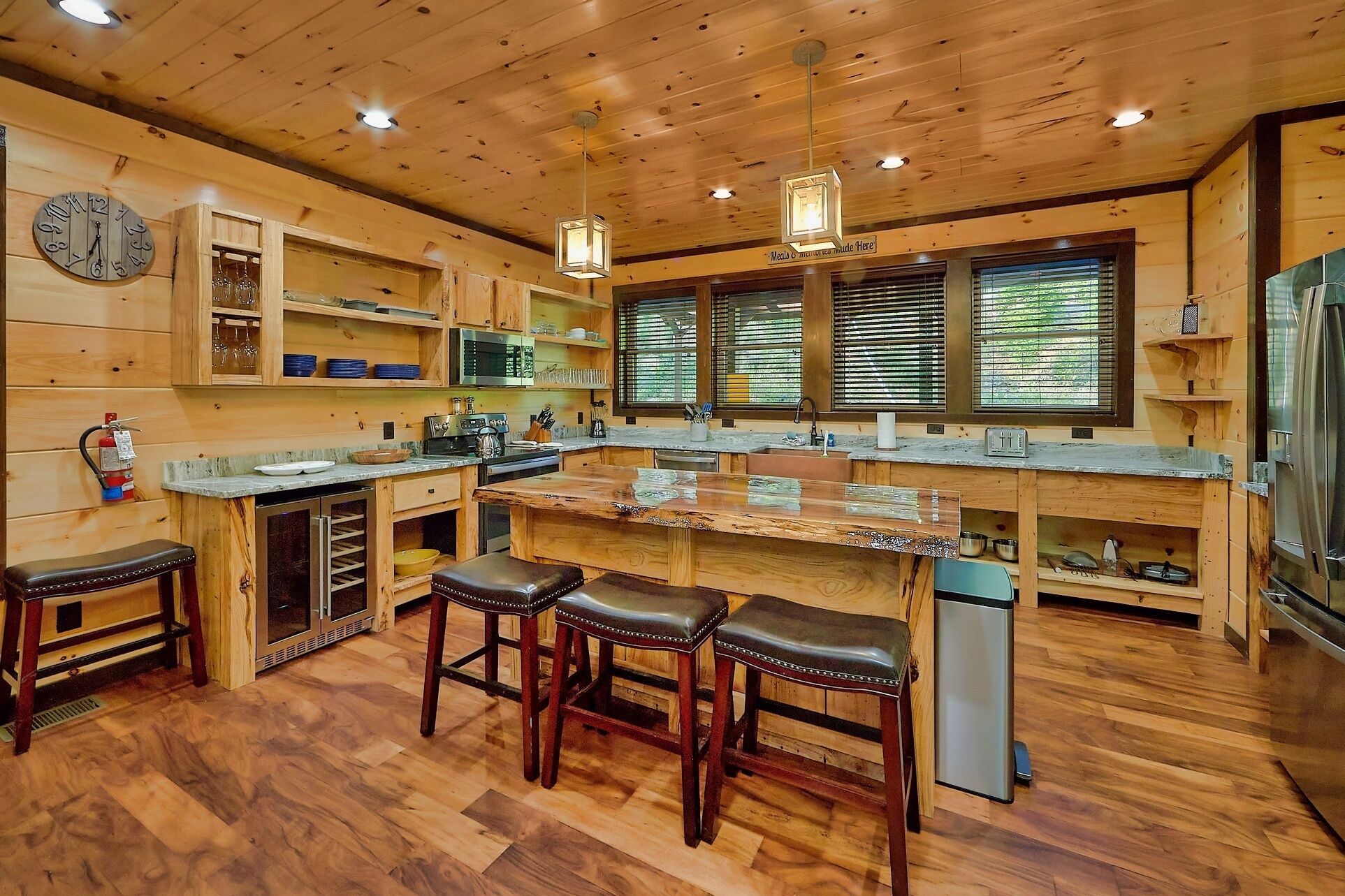 A spacious kitchen with wooden cabinetry, a central island with stools, a microwave, and a refrigerator.
