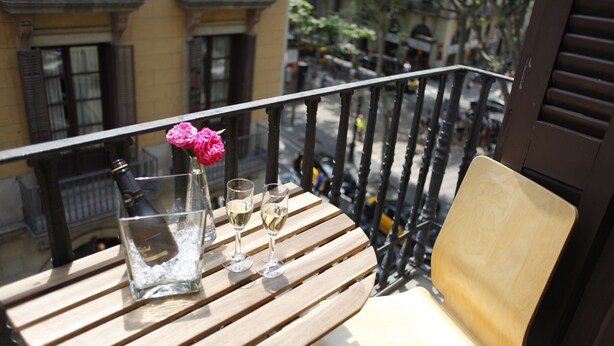 A wooden table with a bottle and glasses on a balcony. - Apartment Colom 1- (Barcelona)