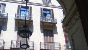 A building with multiple balconies, a sign for 'SOUVENS REIAL', and a 'D' sign indicating a business. - Apartment Colom 1- (Barcelona)