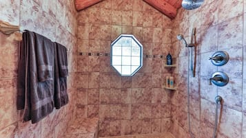 Une salle de douche dotée d’un plafond en pente, d’une fenêtre et d’un porte-serviettes.