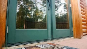 A wooden exterior with a green door and a welcome mat.