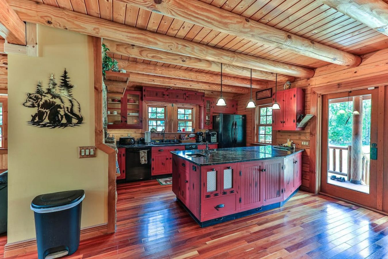 A spacious kitchen with wooden cabinets, a large island, and a view of the outdoors through the windows.