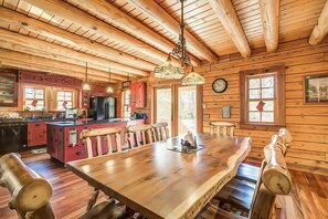Una cabaña espaciosa de madera con un gran comedor, vigas de madera en el techo y una zona de cocina con armarios rojos.