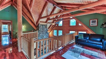 A spacious loft with a wooden staircase, a stone wall, and a blue leather sofa.