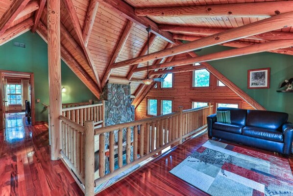 A spacious loft with a wooden staircase, a stone wall, and a blue leather sofa.