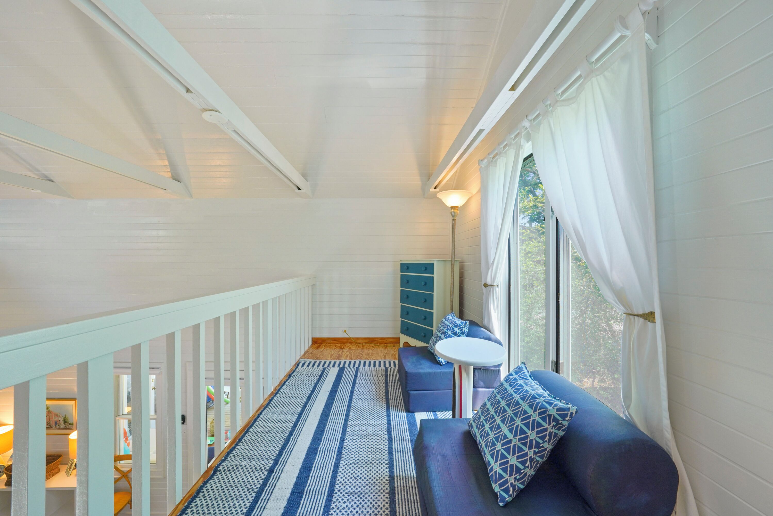 Una habitación acogedora con un sofá azul, una mesita redonda y un tapete a rayas.