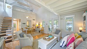 A spacious living area with a staircase, a dining area, and a cozy seating arrangement. - Just 5 Houses to Beach in Seaside! Sleeps Six + 2 Adult Bikes! (Santa Rosa Beach)