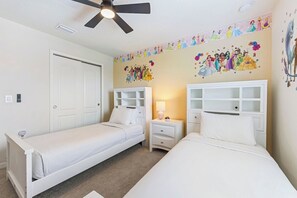 A bedroom with two single beds, white headboards, a ceiling fan, and a wall mural.