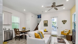 A modern living room with a sofa, dining table, and a ceiling fan. - Cozy Margaritaville Cottage, Near Disney + Universal! (Kissimmee)