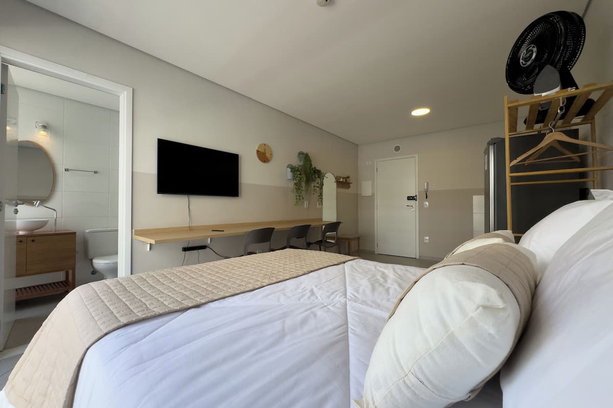 Une chambre d’hôtel moderne équipée d’un lit, d’un bureau, d’une chaise, d’une télévision et d’un ventilateur.