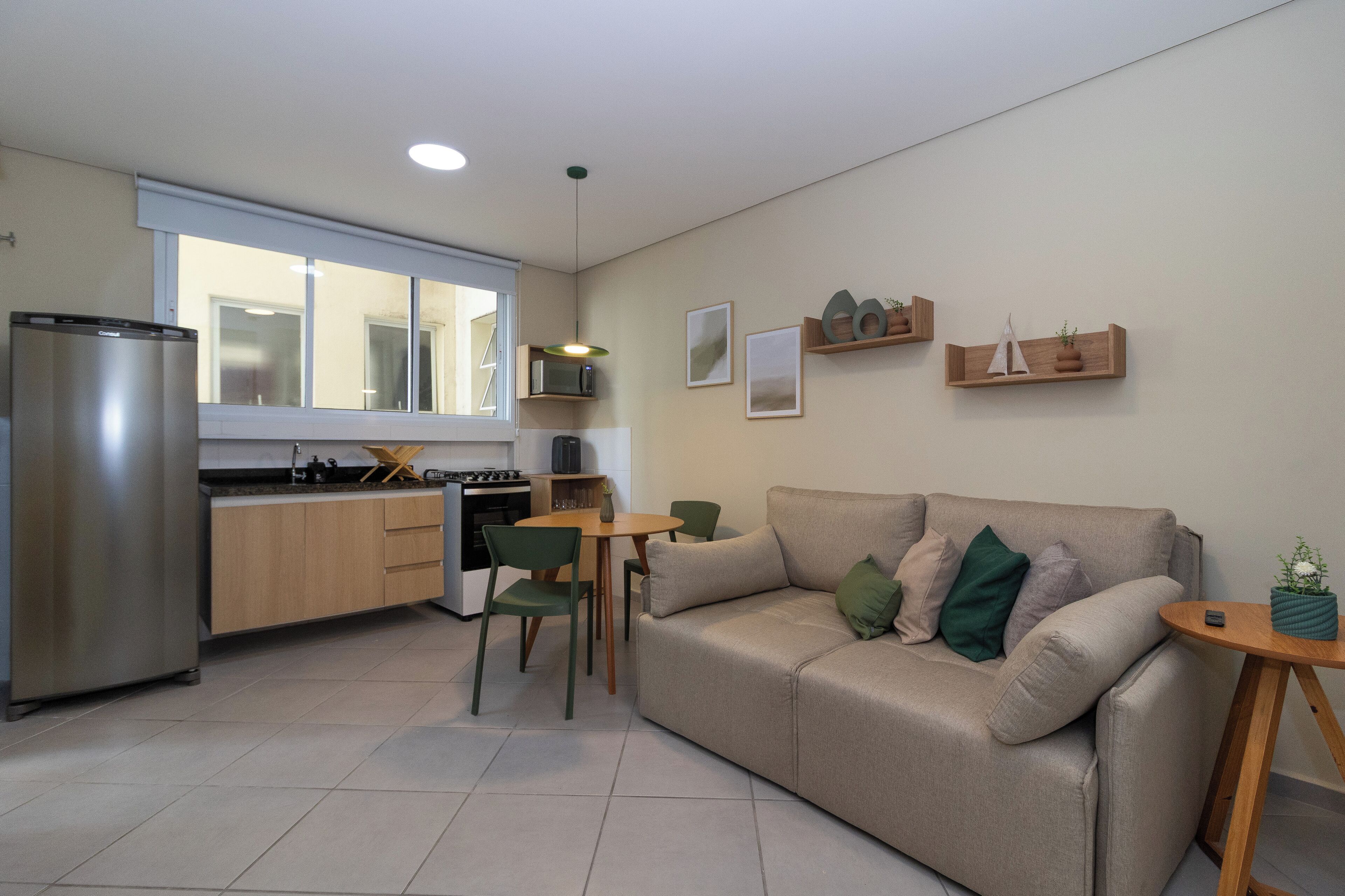 A modern kitchen with a refrigerator, stove, and dining area with chairs and a table.