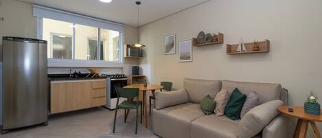 A modern kitchen with a refrigerator, stove, and dining area with chairs and a table.