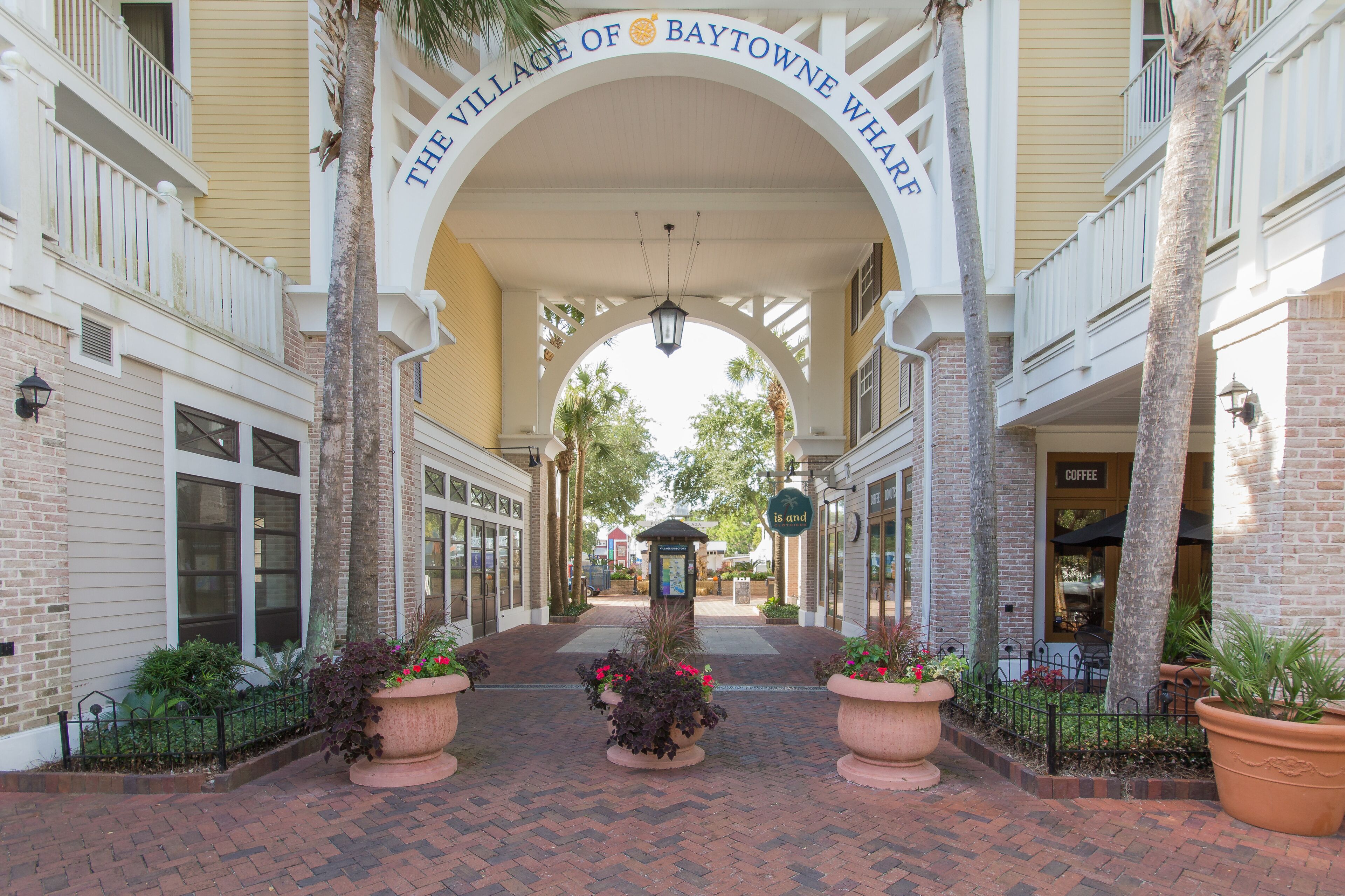 Un sendero de ladrillo que conduce a un edificio con un cartel que dice "The Village of Baytowne Wharf".