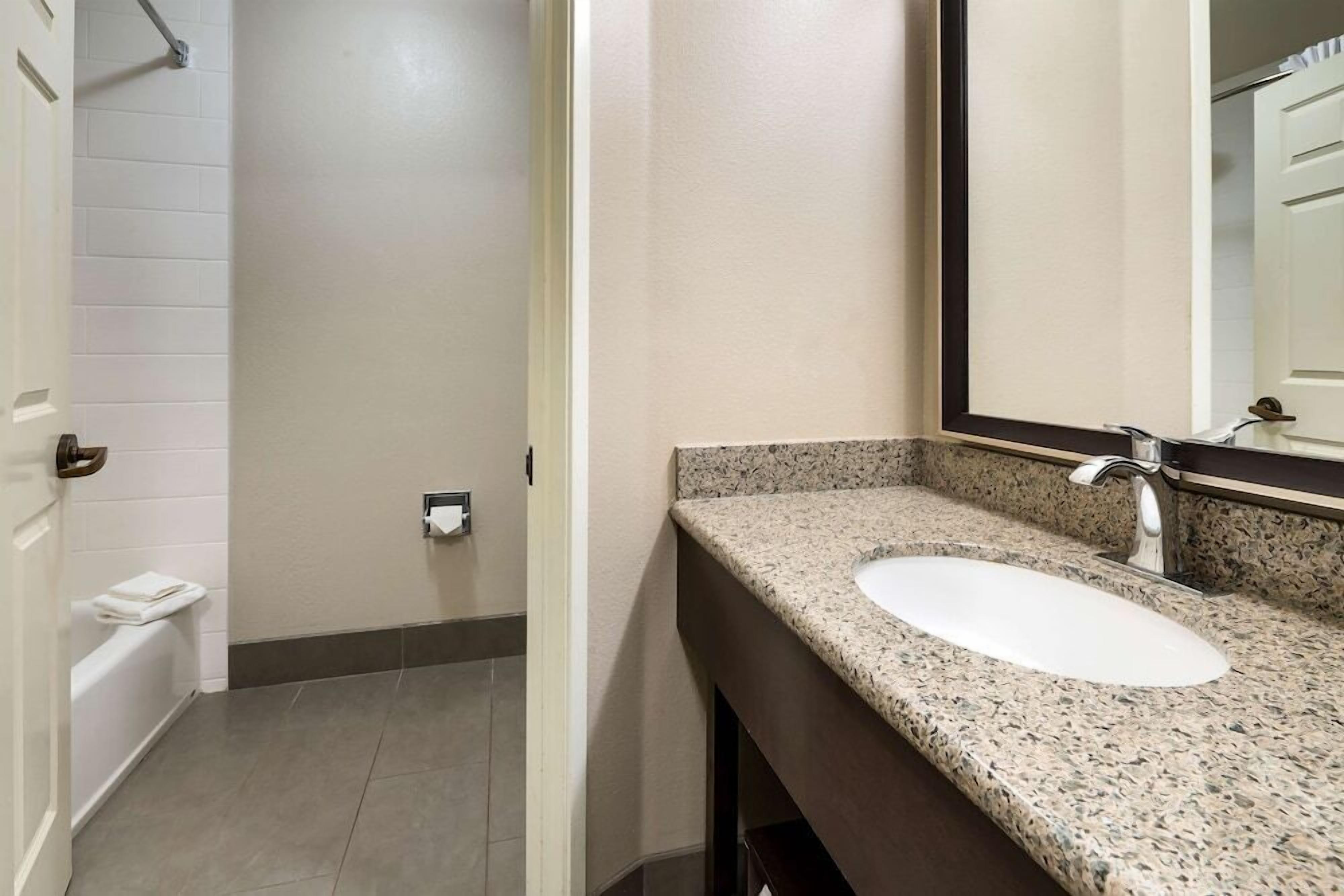 A bathroom with a white sink, granite countertop, and a mirror.