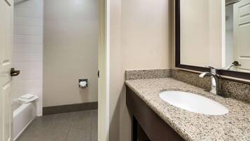 A bathroom with a white sink, granite countertop, and a mirror.
