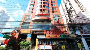 A multi-story building with various commercial establishments on the ground floor, including a fitness center and a restaurant. - Reddoorz @ The Providence Tower (Manila)