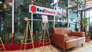A RedDoorz sign, a tripod stand, and a brown leather sofa in a room with tiled flooring. - Reddoorz @ The Providence Tower (Manila)