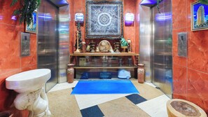 A bathroom with a marble floor, a sink, a mirror, and a decorative shelf with various items. - Reddoorz @ The Providence Tower (Manila)