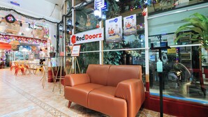 A RedDoorz store with a brown leather couch in front, a glass display case, and a sign advertising a safe and comfortable stay. - Reddoorz @ The Providence Tower (Manila)