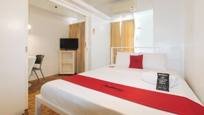 Una habitación de hotel con cama, televisión, escritorio y silla.