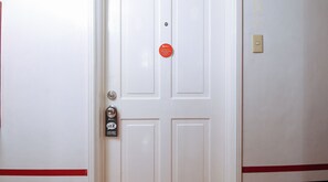 A hotel room door with a RedDoor's logo, a do not disturb sign, and a keycard reader. - Reddoorz @ The Providence Tower (Manila)