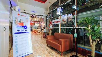 Lobby de hotel RedDoorz com sofá de couro marrom, balcão de recepção e placa que indica certificação HygienePass.
