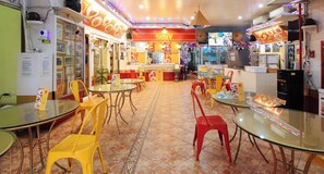 A restaurant interior with multiple tables and chairs, a counter with a menu, and a television screen. - Reddoorz @ The Providence Tower (Manila)