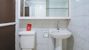 A bathroom with a toilet, a sink, and a mirror. - Reddoorz @ The Providence Tower (Manila)
