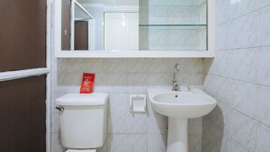 A bathroom with a toilet, a sink, and a mirror. - Reddoorz @ The Providence Tower (Manila)