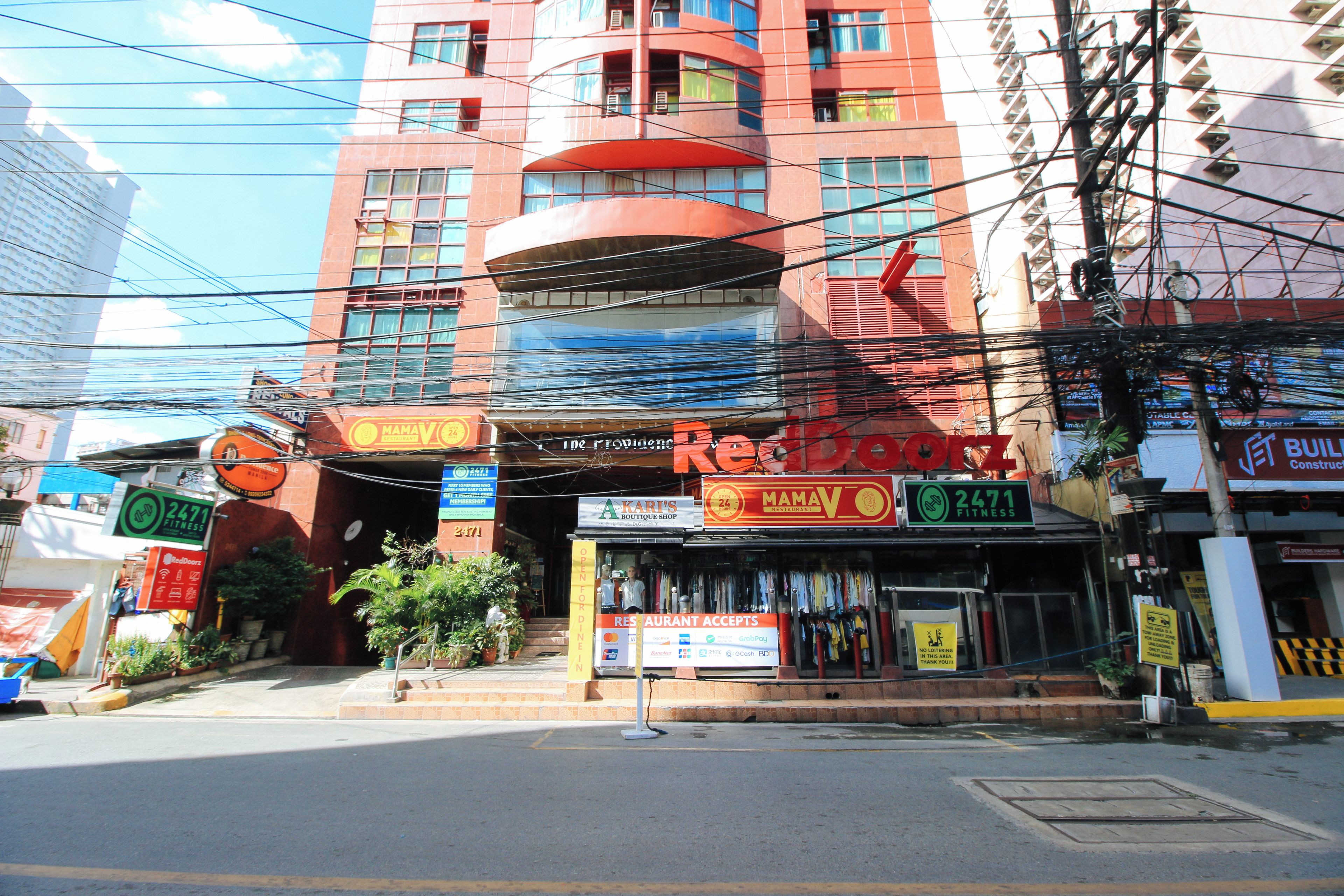 Um edifício de vários andares com diversos estabelecimentos comerciais no térreo, incluindo academia, restaurante e loja boutique.