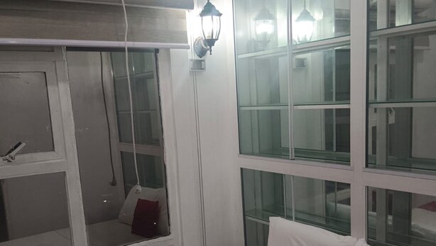 A hotel room with a bed, a window, a wall-mounted air conditioner, and a lamp. - Reddoorz @ The Providence Tower (Manila)