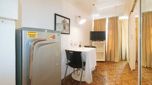 A compact room with a kitchenette, a dining area, and a television. - Reddoorz @ The Providence Tower (Manila)