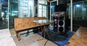 A seating area with a bench and a small table, a jukebox, and a glass partition. - Reddoorz @ The Providence Tower (Manila)
