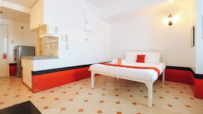 A hotel room with a bed, a small kitchenette, a bathroom, and a red and black accent wall. - Reddoorz @ The Providence Tower (Manila)
