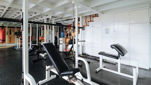 A gym with weightlifting equipment, benches, and a mirrored wall. - Reddoorz @ The Providence Tower (Manila)