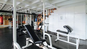 A gym with weightlifting equipment, benches, and a mirrored wall. - Reddoorz @ The Providence Tower (Manila)