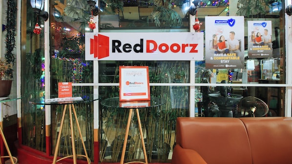 A RedDoorz sign with a HygienePass badge, a glass table with a red sign, and a brown leather chair. - Reddoorz @ The Providence Tower (Manila)