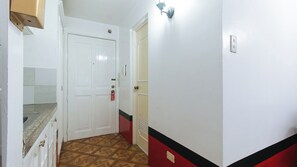A narrow hallway with a white door, a red and black stripe on the wall, and a light switch. - Reddoorz @ The Providence Tower (Manila)