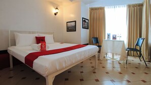 A hotel room with a neatly made bed, a small table, and two chairs. - Reddoorz @ The Providence Tower (Manila)