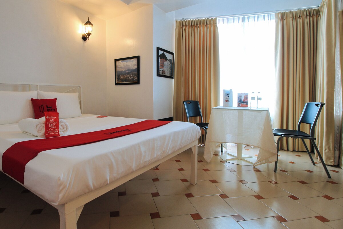 A hotel room with a neatly made bed, a small table, and two chairs.