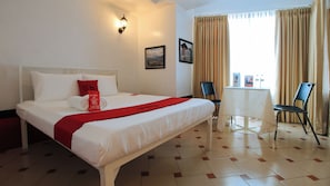 A hotel room with a neatly made bed, a small table, and two chairs. - Reddoorz @ The Providence Tower (Manila)