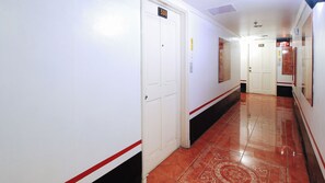 A hotel corridor with white walls, red and black striped flooring, and doors numbered 506 and 510. - Reddoorz @ The Providence Tower (Manila)